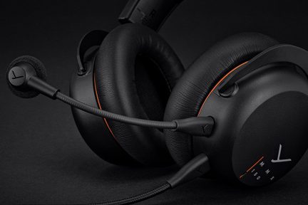 Casque audio noir avec coussinets circulaires rembourrés, arceau visible, micro flexible détachable, détails orange, vue rapprochée
