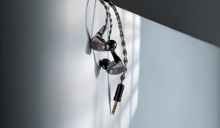 Metallic gray and black in-ear headphones made of metal with red logos, silver braided cable ending in a gold-plated jack connector, close-up front view