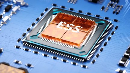 Vue rapprochée d'une puce électronique rectangulaire avec un boîtier noir, un centre orange marqué "ESS" et un circuit bleu