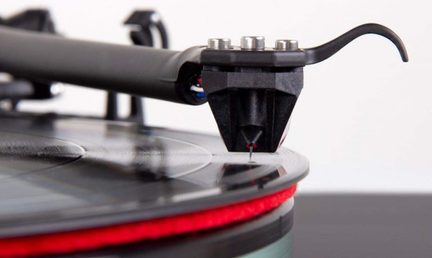 Giradischi nero con braccio di lettura e puntina rossa su disco in vinile, primo piano laterale